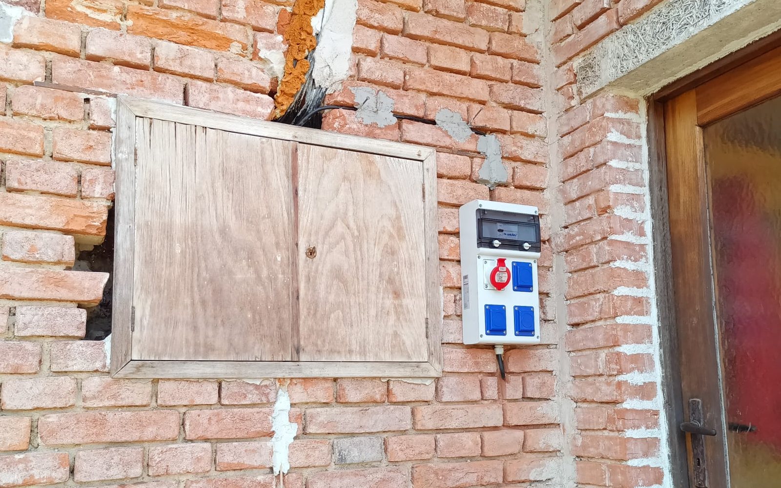 Rozvaděč s jističi a měřicím modulem osazený na cihlové stěně